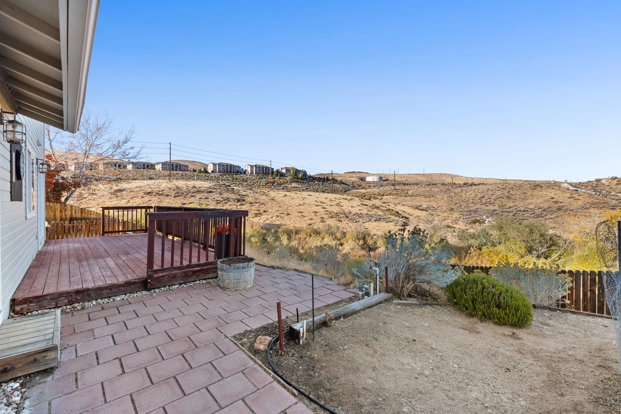 Deck and fenced backyard overlooking open land